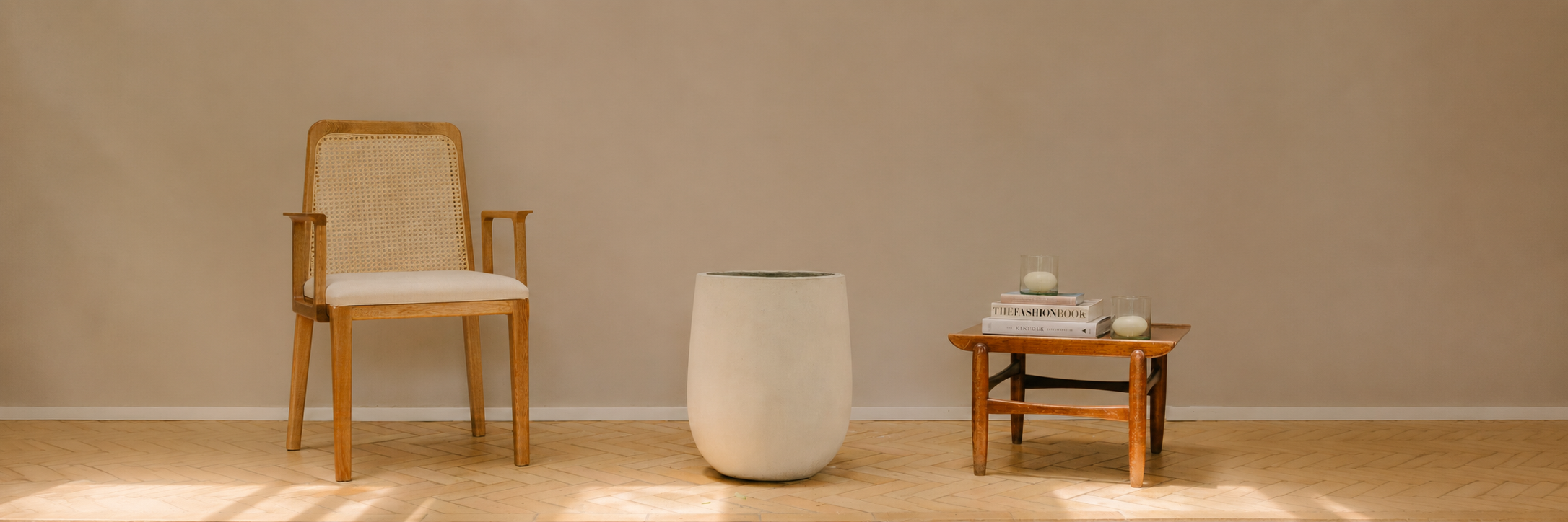 Matera blanca junto a una silla y mesa de madera, colección Materas de Pistilo & Gracia.