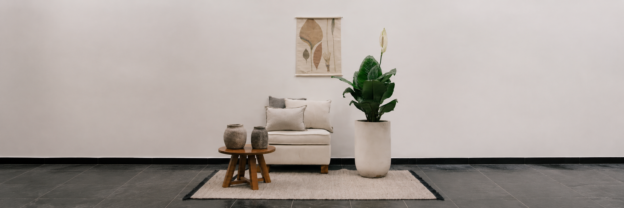 Planta Spatofilio en matera clara junto a una sala con mesa auxiliar y piezas decorativas, colección Tamaño XL de Pistilo & Gracia.