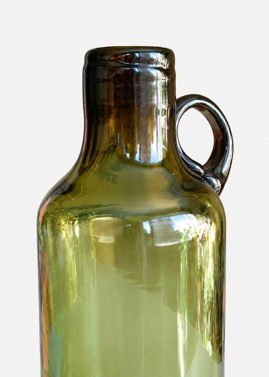 Detalle de Botella con Asa en vidrio soplado reciclado, con cuello oscuro y asa lateral.