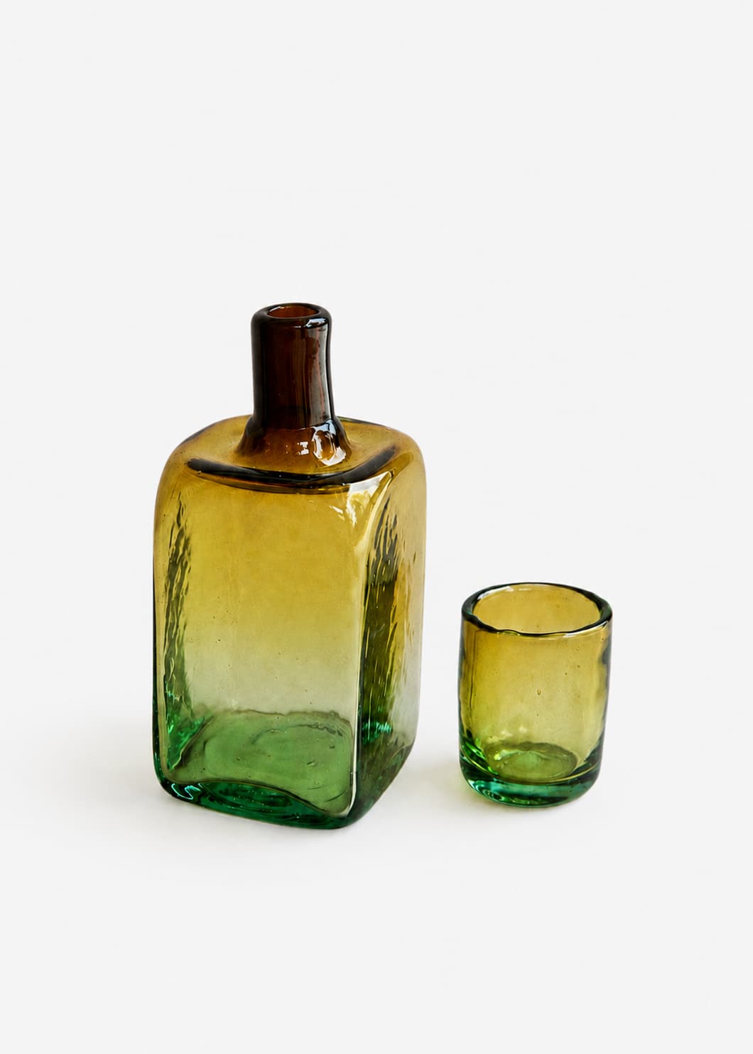 Botella para nochero con vaso en vidrio soplado bicolor, con vaso separado junto a la pieza.