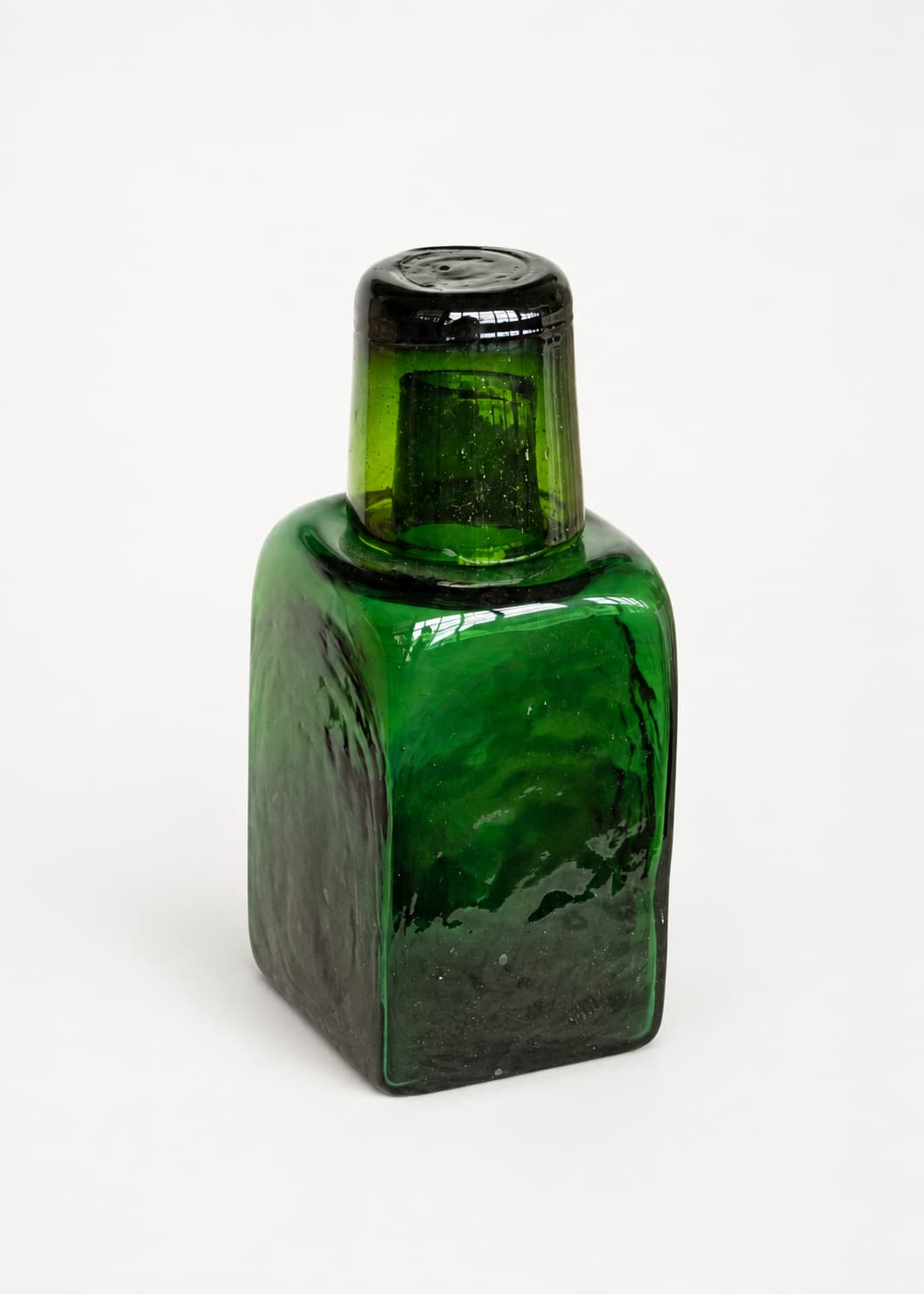Botella para nochero con vaso en vidrio soplado verde, con el vaso superior funcionando como tapa.