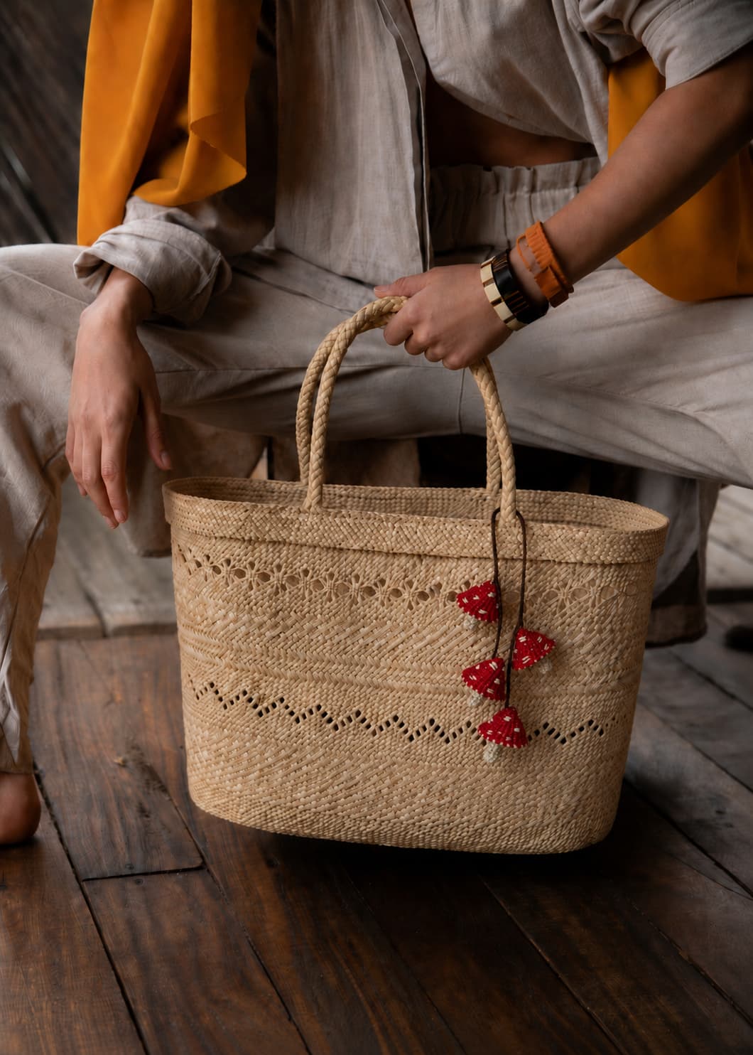 Charm de hongos rojos tejido en palma de iraca sobre bolso artesanal de fibras naturales.