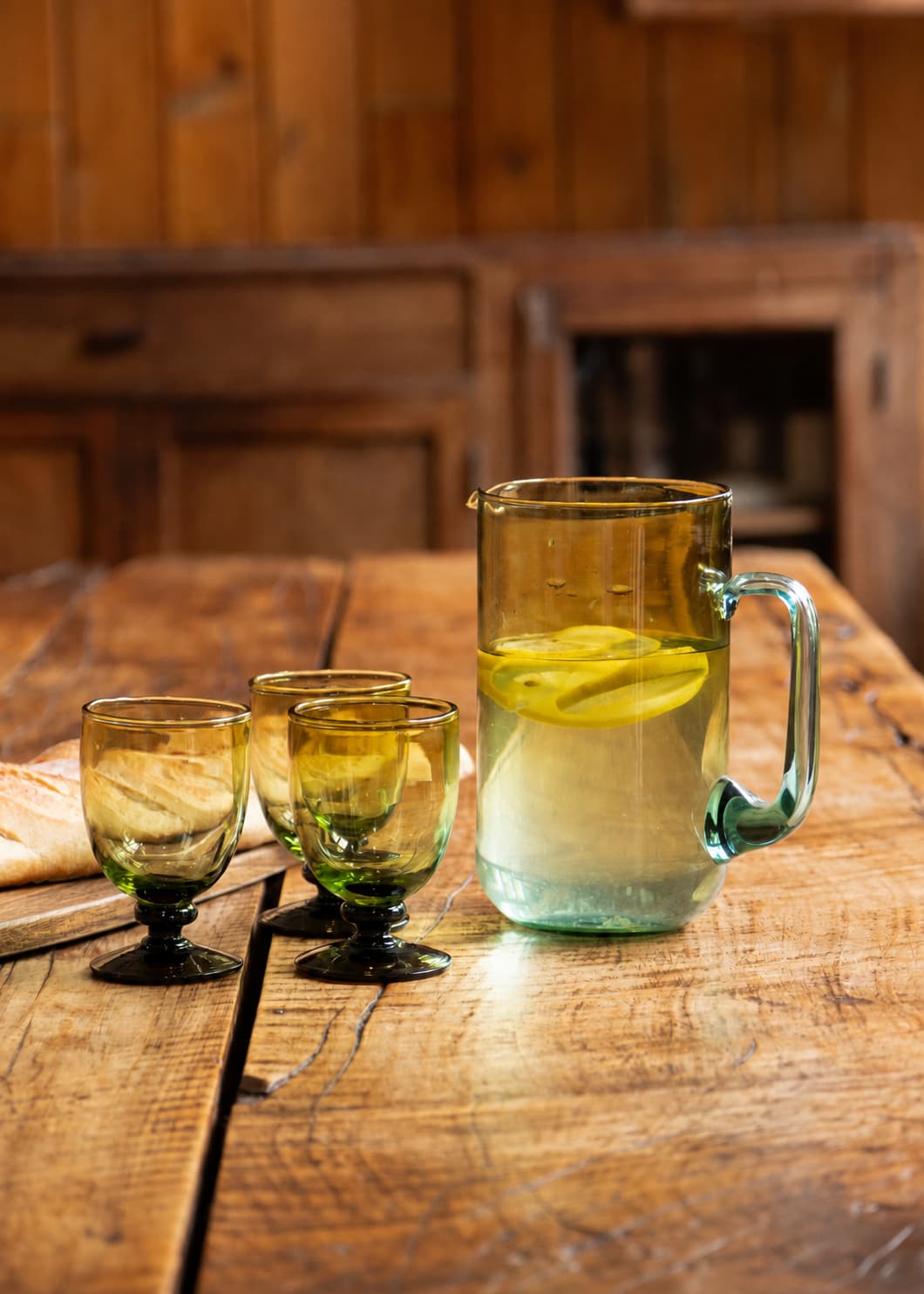 Jarra de Agua en vidrio soplado sobre mesa de madera en ambiente de cocina.