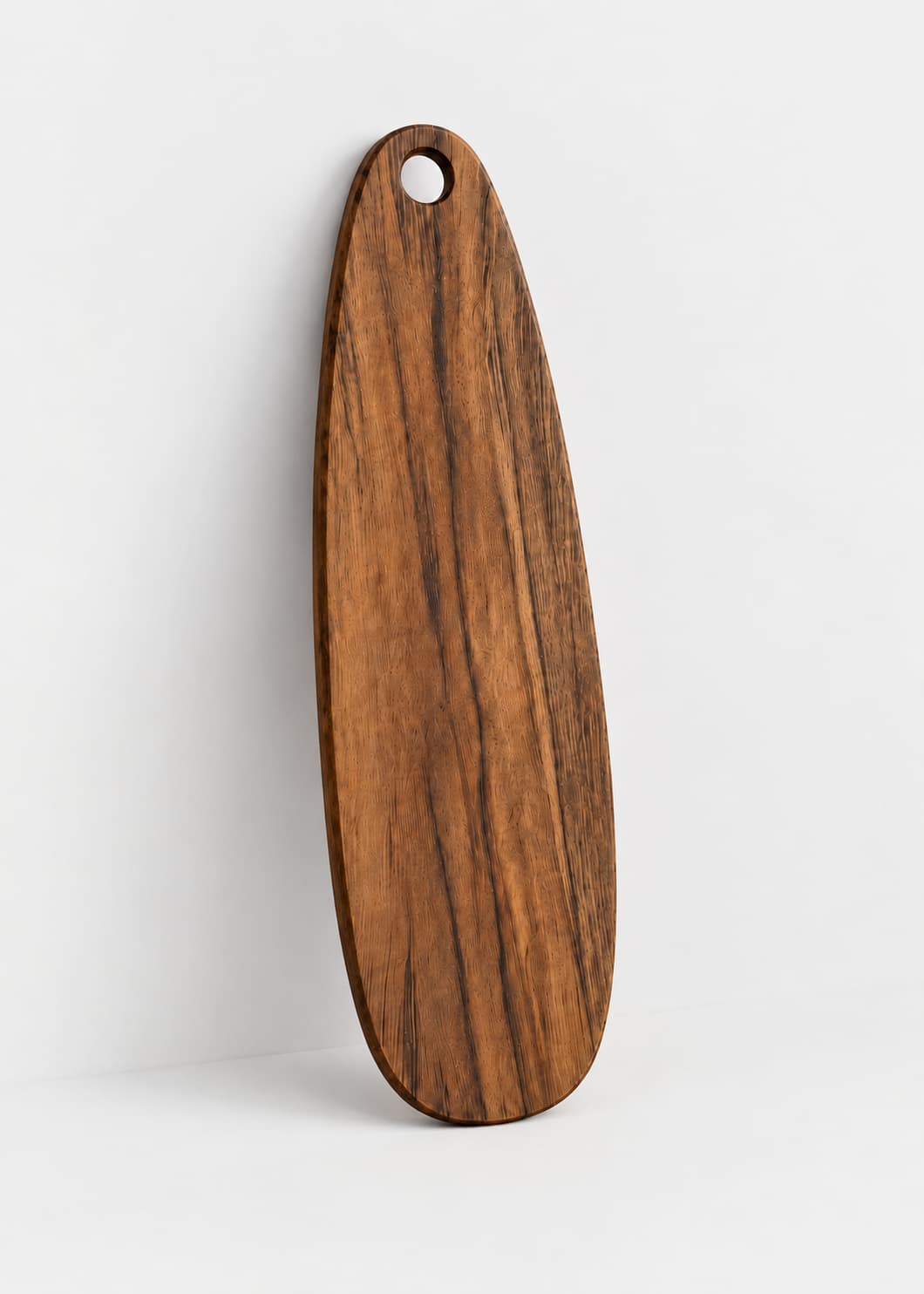 Tabla de madera mediana artesanal de forma alargada con orificio superior, vista frontal.