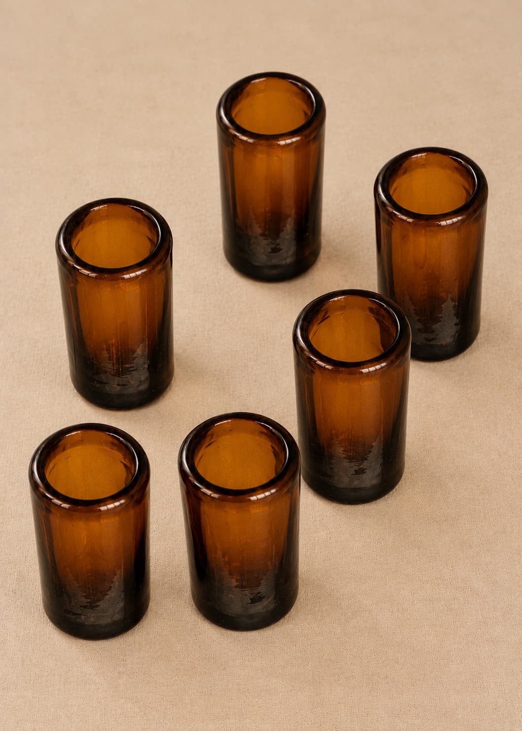 Set de seis vasos de shot artesanales en vidrio ámbar, vista superior oblicua.