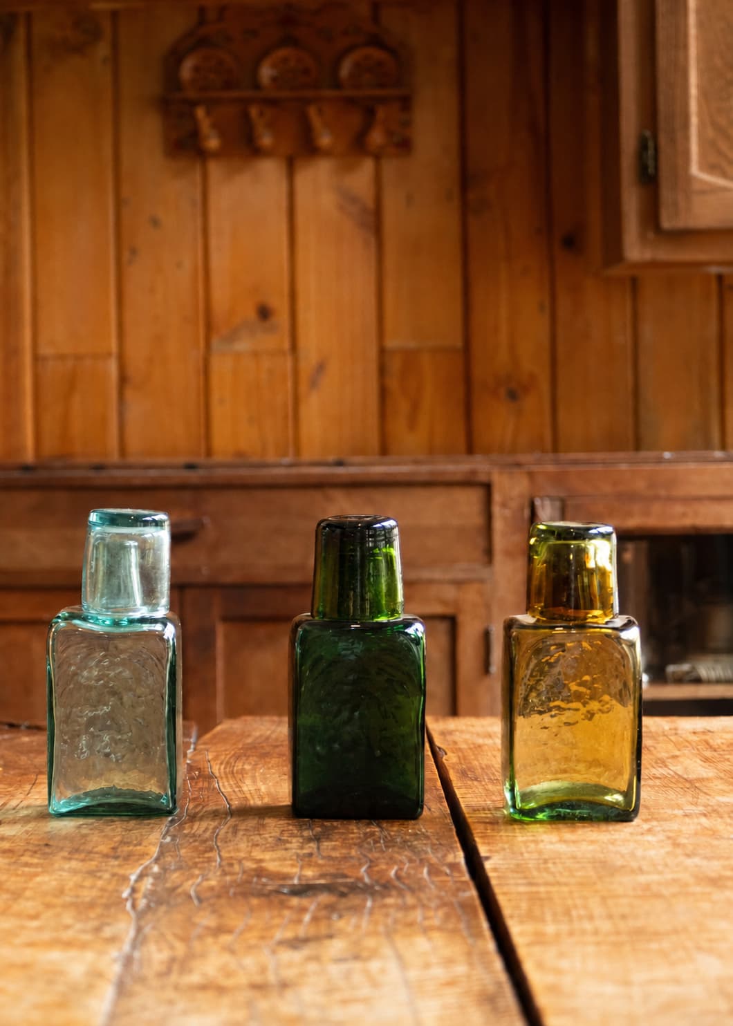 Tres botellas para nochero de vidrio soplado en azul agua, verde y ámbar, cada una con el vaso superior funcionando como tapa