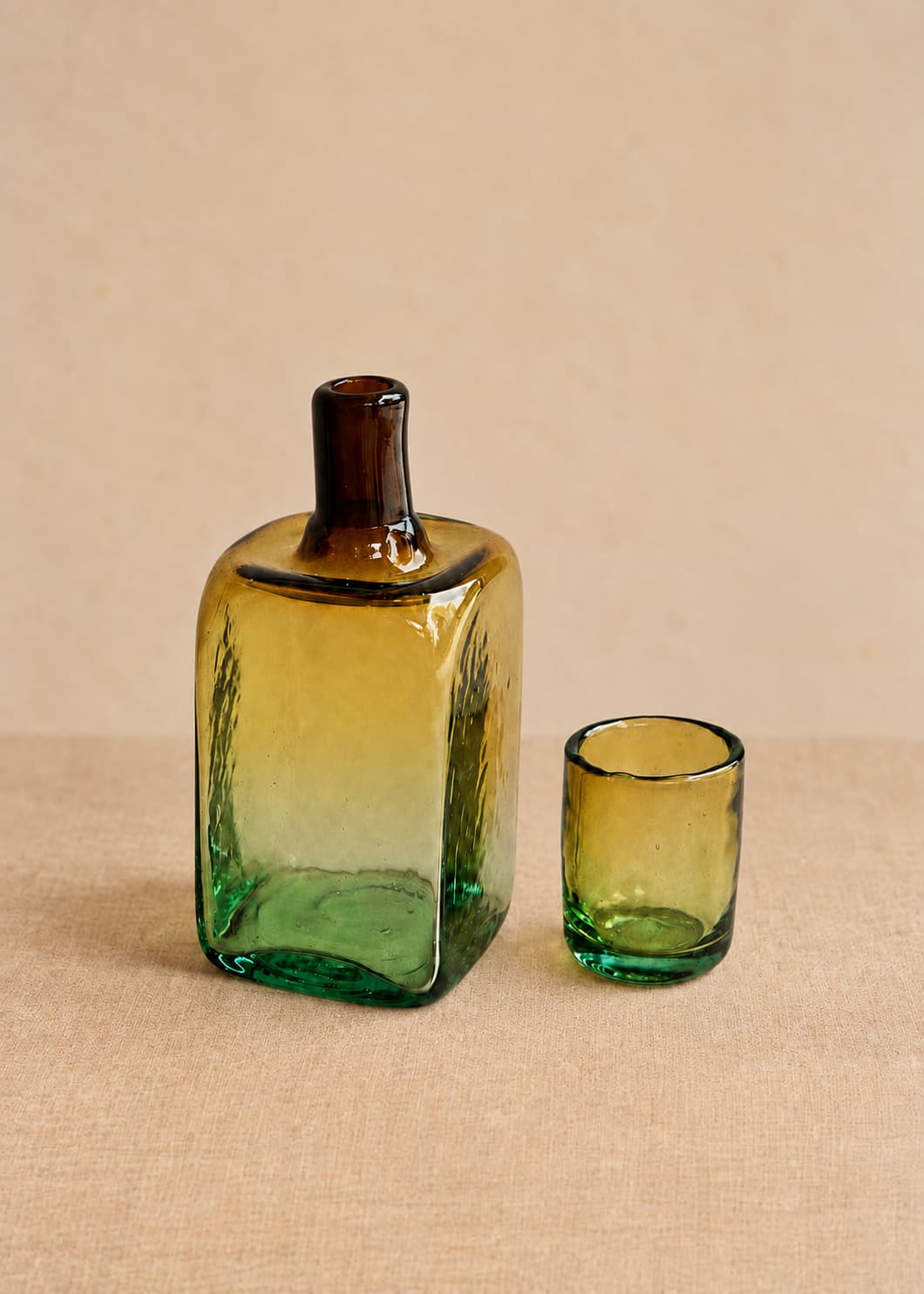Botella para nochero con vaso en vidrio soplado bicolor, con vaso separado junto a la pieza.