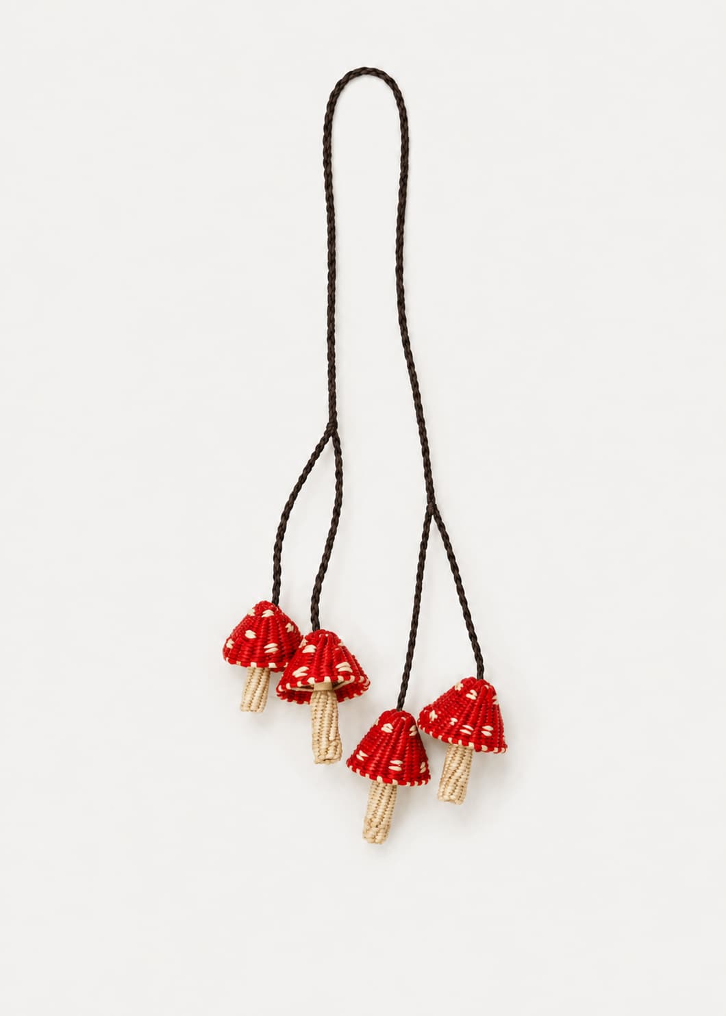 Charm de cuatro hongos rojos tejidos en palma de iraca con cordones trenzados.