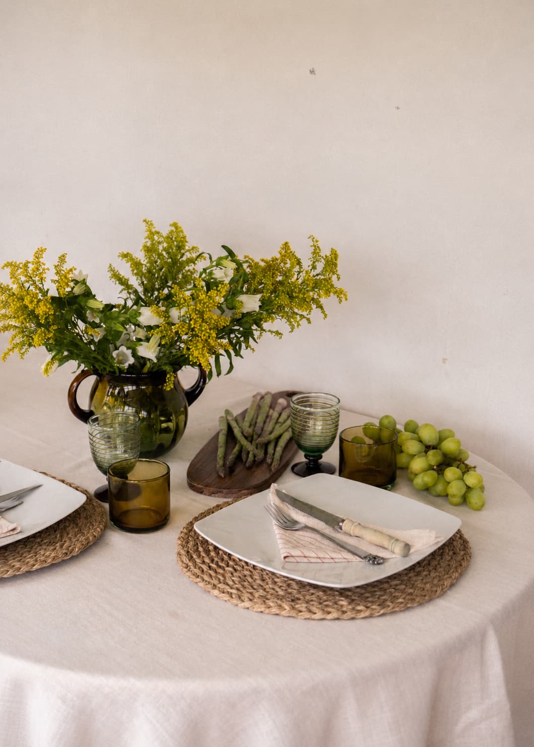 Florero Orejas Ámbar en vidrio soplado con flores amarillas sobre mesa servida.